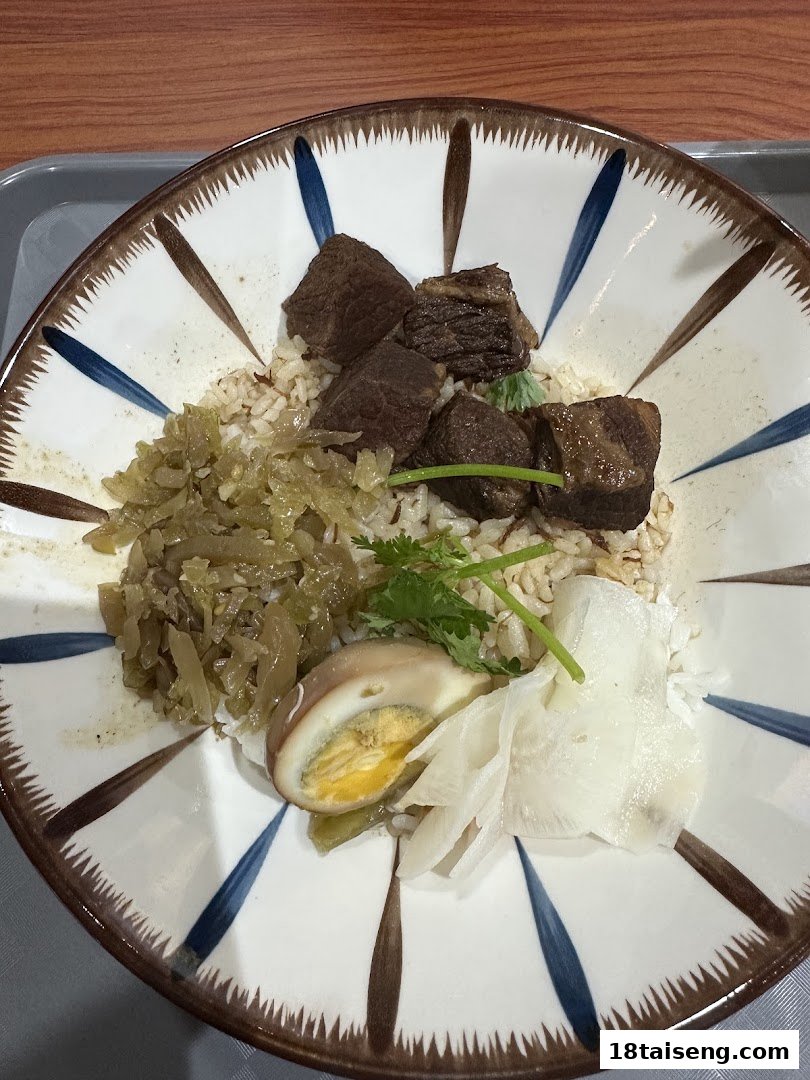 A delicious bowl of braised beef with rice, pickled vegetables, and a soy-marinated egg.