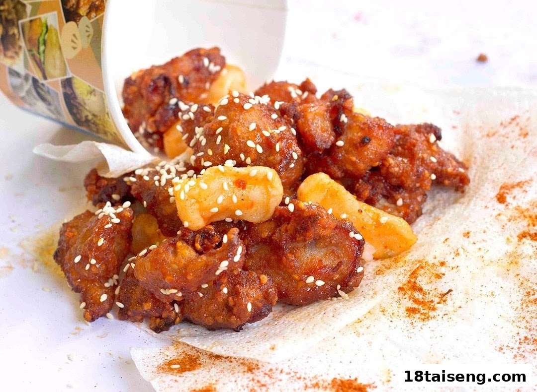 Close-up of crispy fried chicken pieces with rice cakes and sesame seeds, served from a cup.