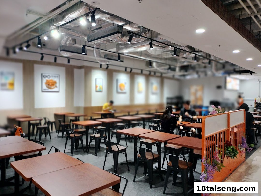 A spacious and modern dining area with numerous tables and chairs, featuring customers and food art on the walls.