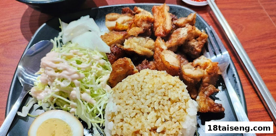 A close-up of a delicious Taiwanese meal featuring crispy fried pork, seasoned rice, and fresh salad.