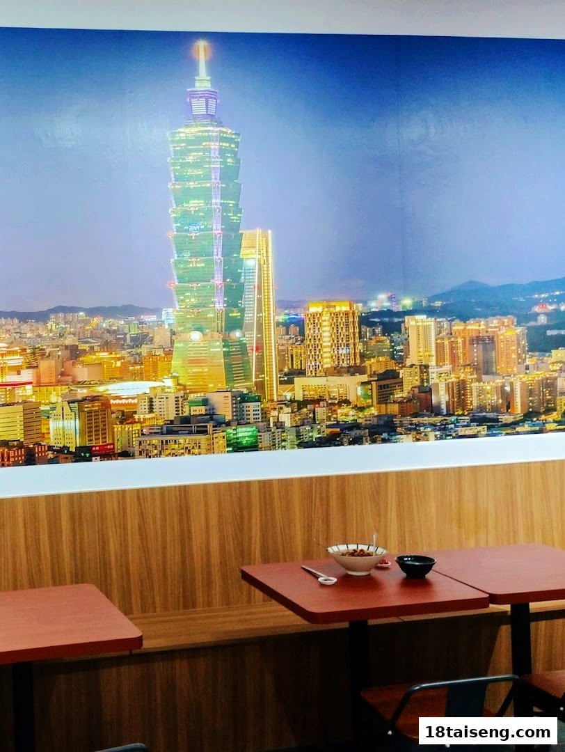 A cozy dining area featuring a large wall mural of the illuminated Taipei 101 skyline at night.