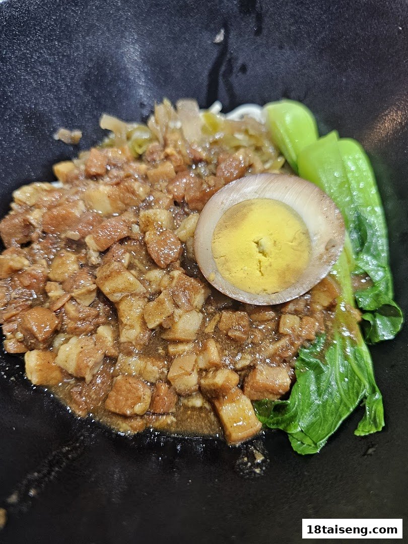 A close-up of Taiwanese braised pork rice (Lu Rou Fan) with a marinated egg and green vegetables.
