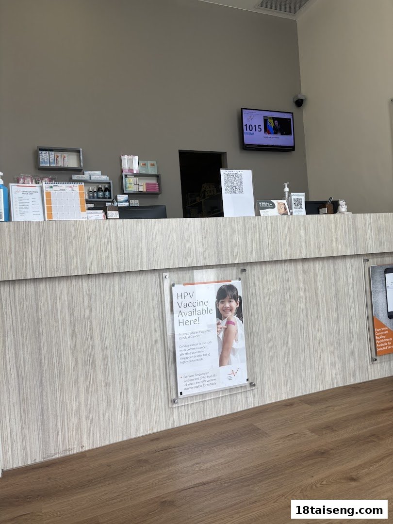 A clean, modern clinic reception area featuring a waiting number screen and health information posters.