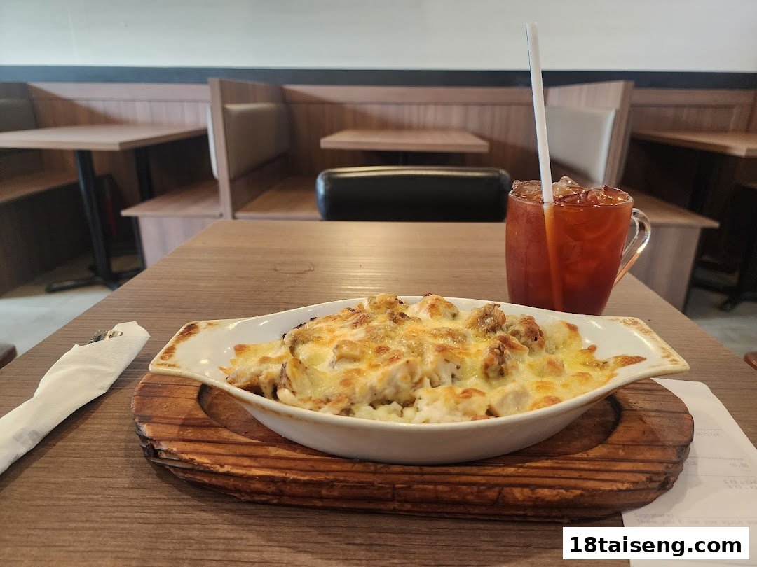 A cheesy baked dish and iced tea on a wooden table in a cozy restaurant setting.