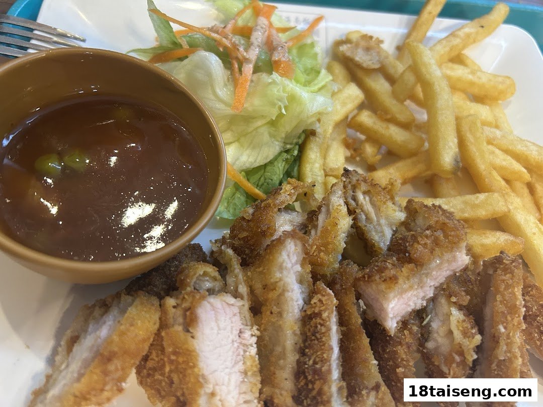 A plate of crispy fried cutlet served with golden fries, fresh salad, and a side of savory sauce.