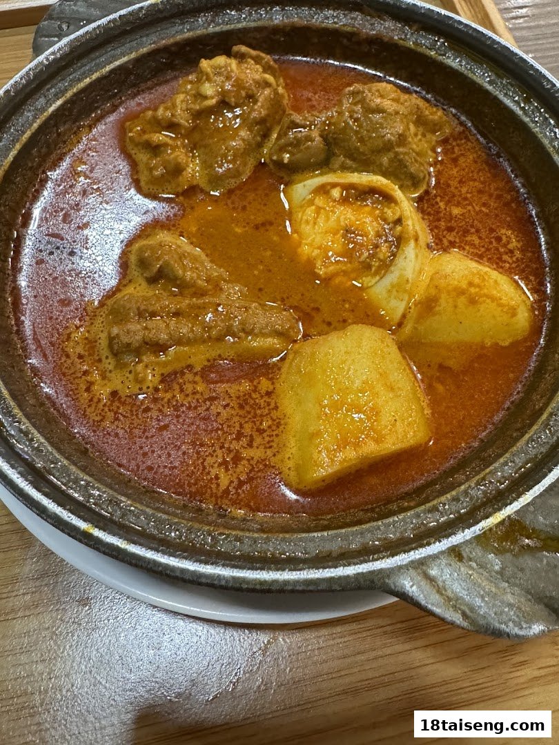 A vibrant hot pot of Hainanese curry chicken with potatoes and egg, served in a traditional claypot.