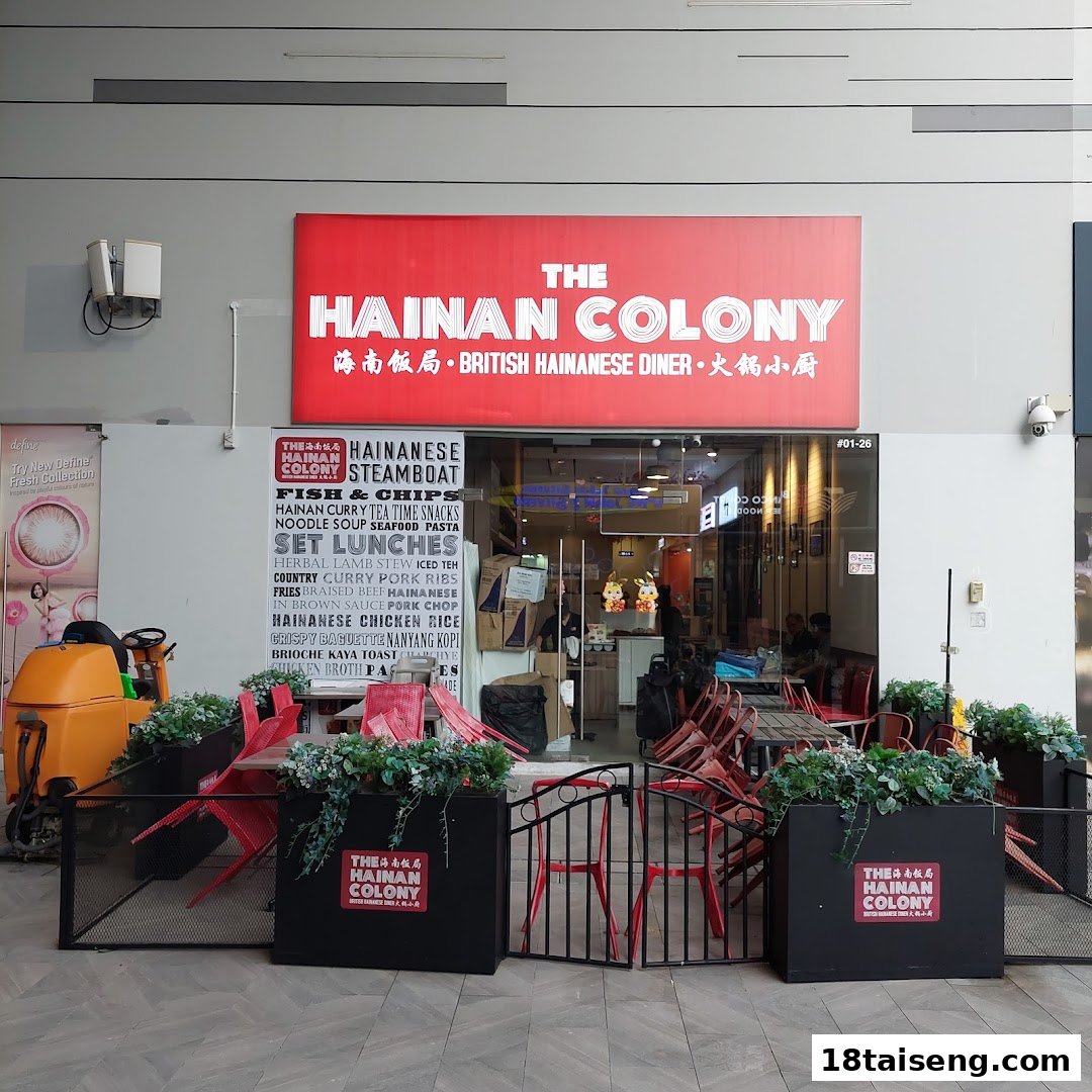 The shopfront of The Hainan Colony, a British Hainanese diner, featuring outdoor seating and a prominent red sign.