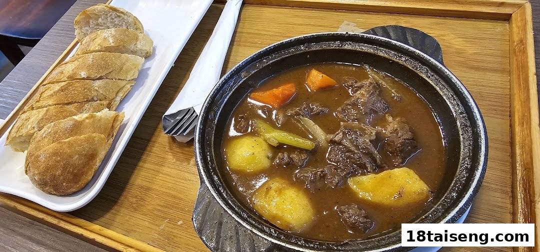 A hearty beef stew with potatoes and carrots, served with sliced baguette on a wooden tray.