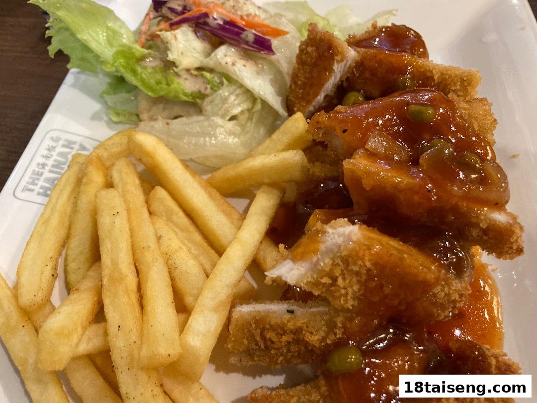 A plate of crispy breaded chicken with sweet and sour sauce, french fries, and a side salad.