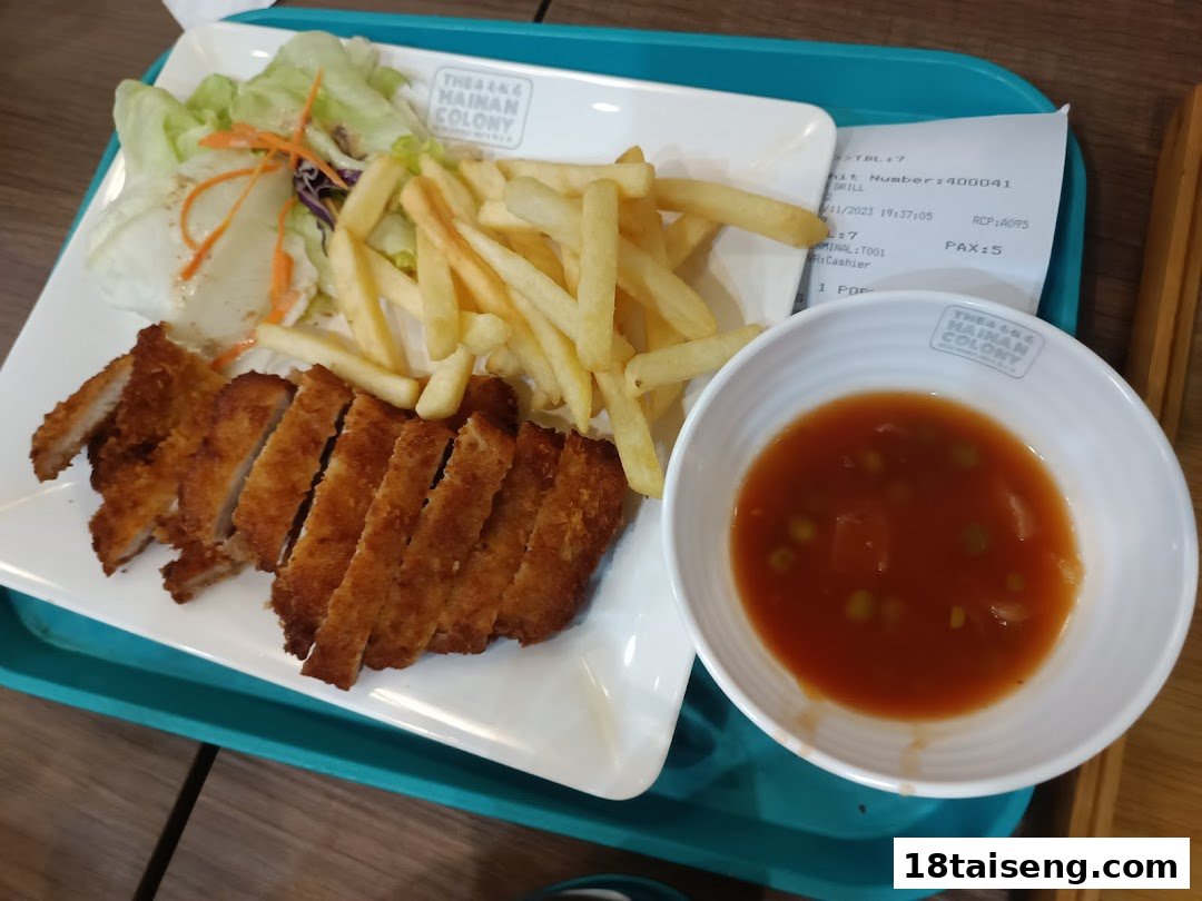 A delicious plate featuring crispy fried chicken cutlet, golden fries, fresh salad, and a sweet and sour sauce.