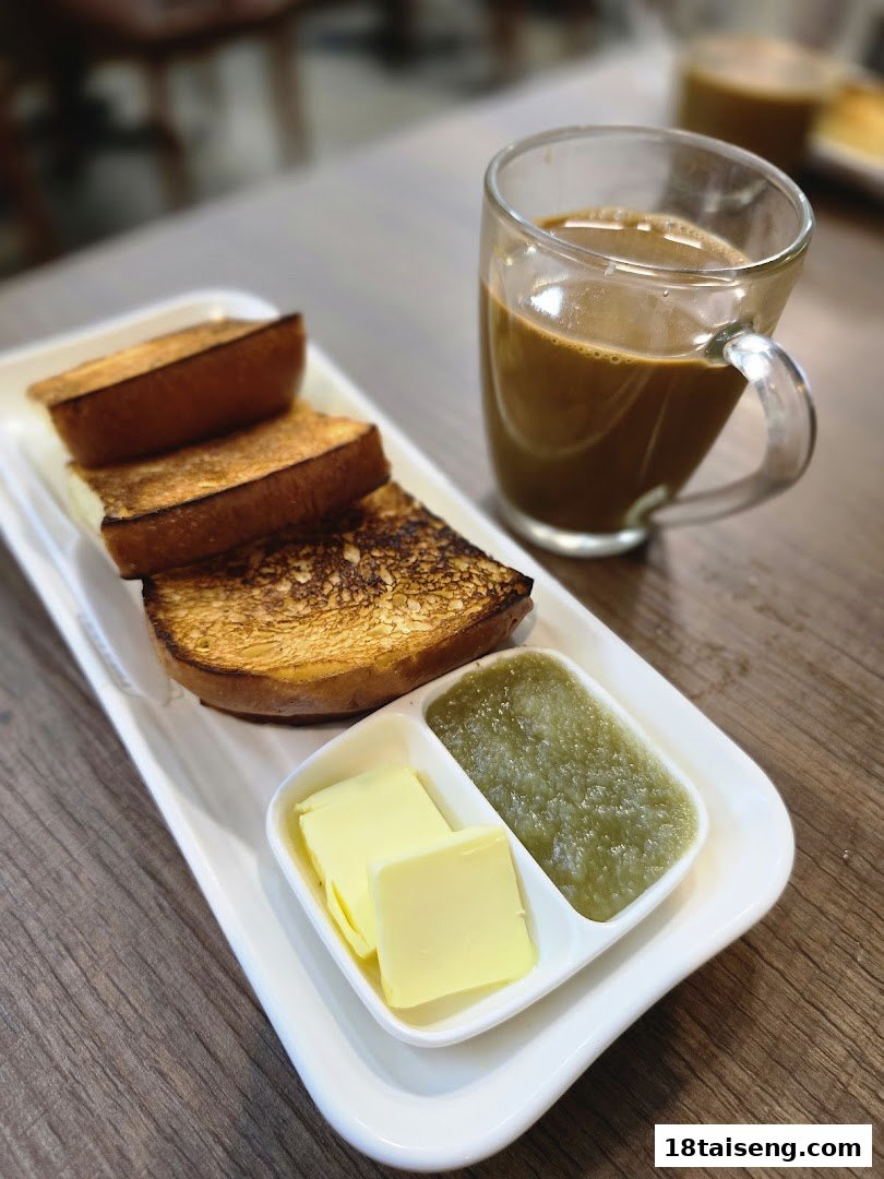 A plate of golden-brown toast with butter, kaya jam, and a glass of coffee.