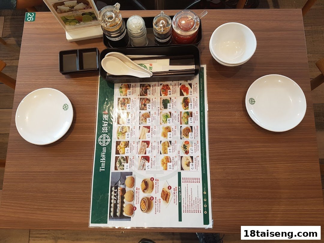A table setting at Tim Ho Wan featuring a detailed menu, plates, and condiments.