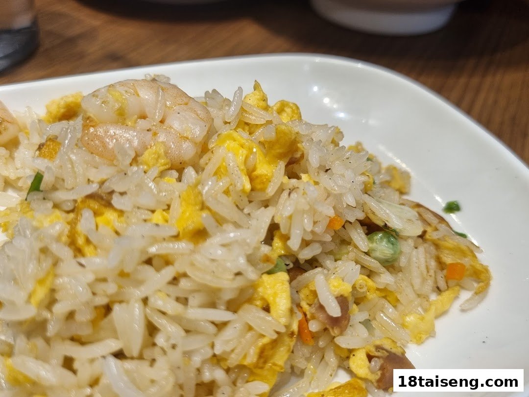 Close-up of delicious shrimp fried rice with egg and vegetables on a white plate.