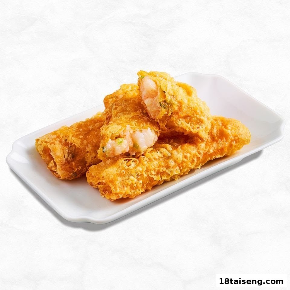 Golden fried shrimp rolls on a white plate, one cut open revealing succulent shrimp.