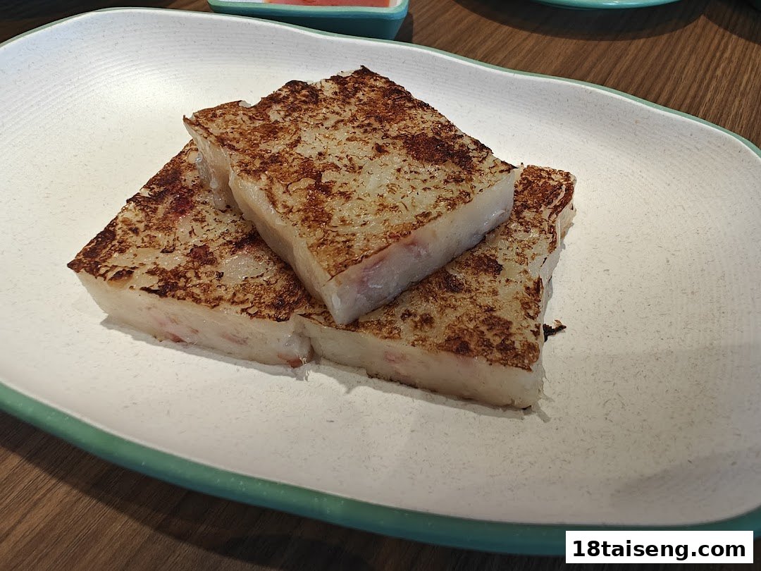 Three pieces of pan-fried turnip cake with crispy edges on a white plate.