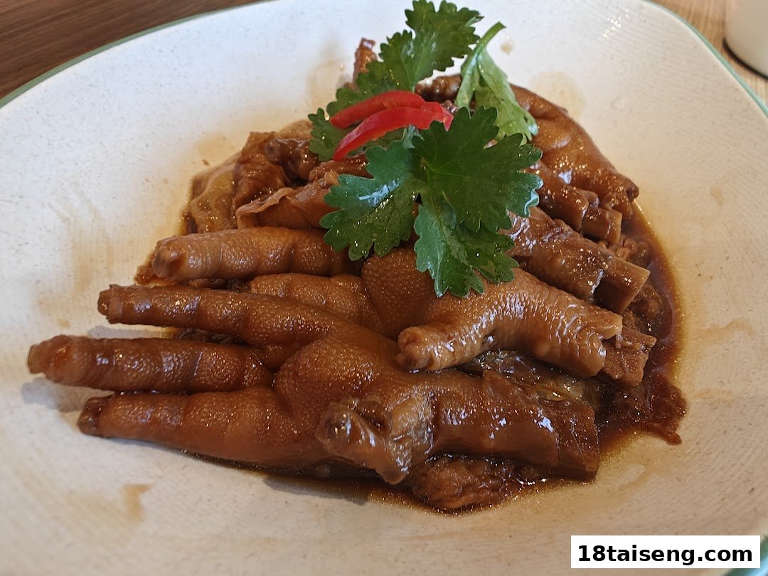 A plate of braised chicken feet garnished with fresh cilantro and red chili.