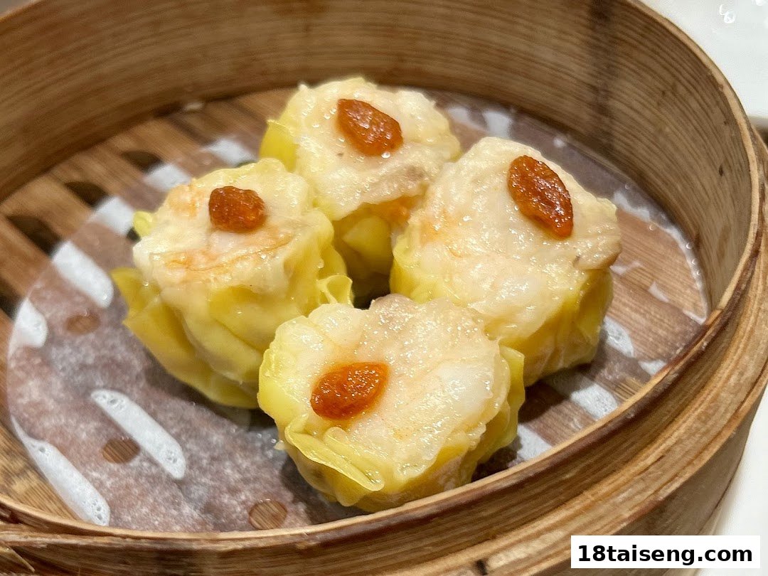 Four pieces of steamed dim sum, likely siu mai, served in a traditional bamboo steamer.