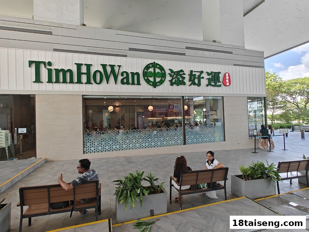 Exterior view of Tim Ho Wan restaurant with green signage, large windows, and outdoor seating area.