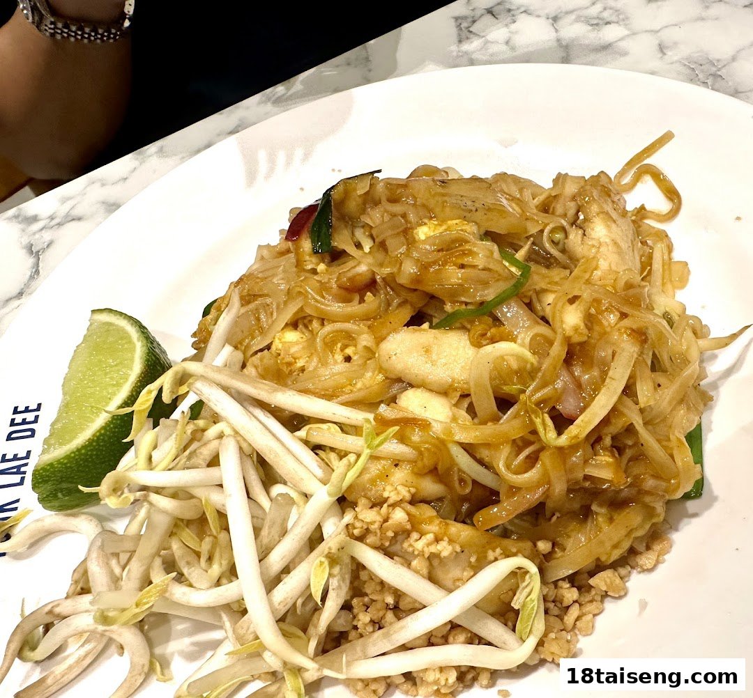 A close-up of a delicious plate of Pad Thai noodles with bean sprouts and a lime wedge.
