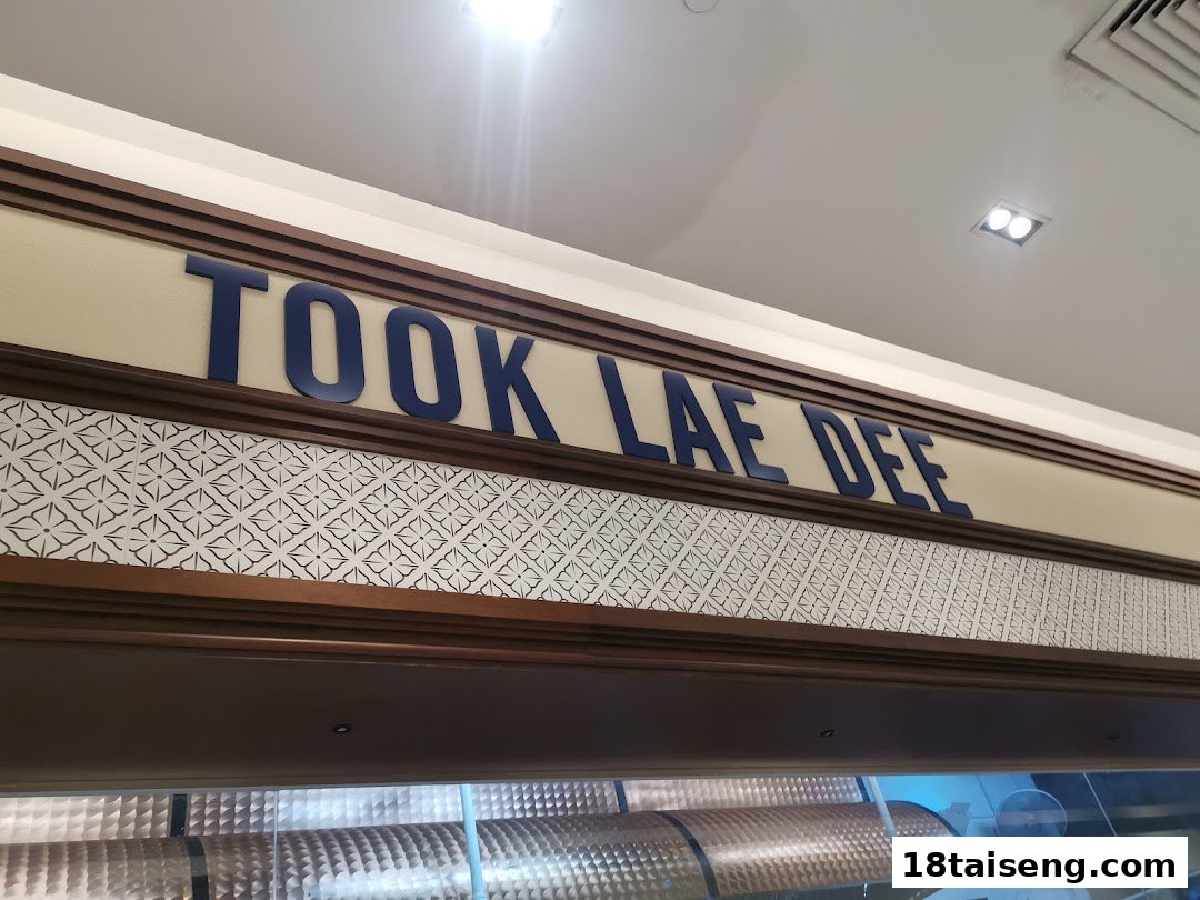 Close-up view of the 'Took Lae Dee' shop sign with decorative patterns above the entrance.