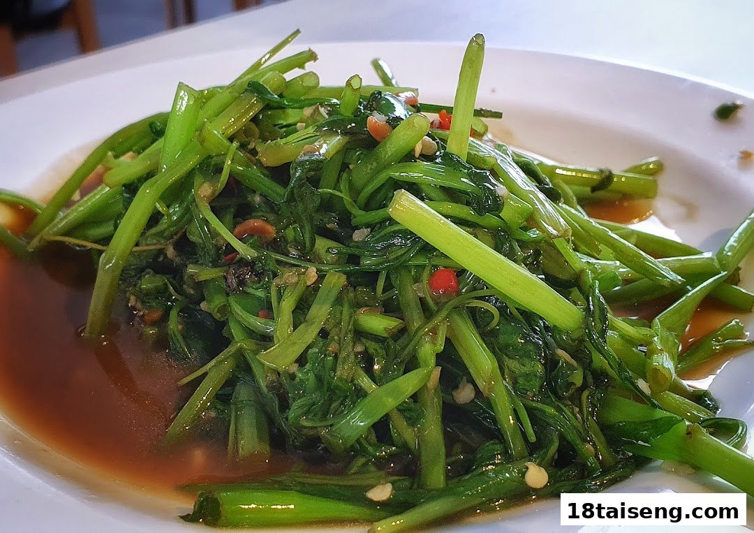 A vibrant plate of stir-fried morning glory with chili and garlic in a savory sauce.