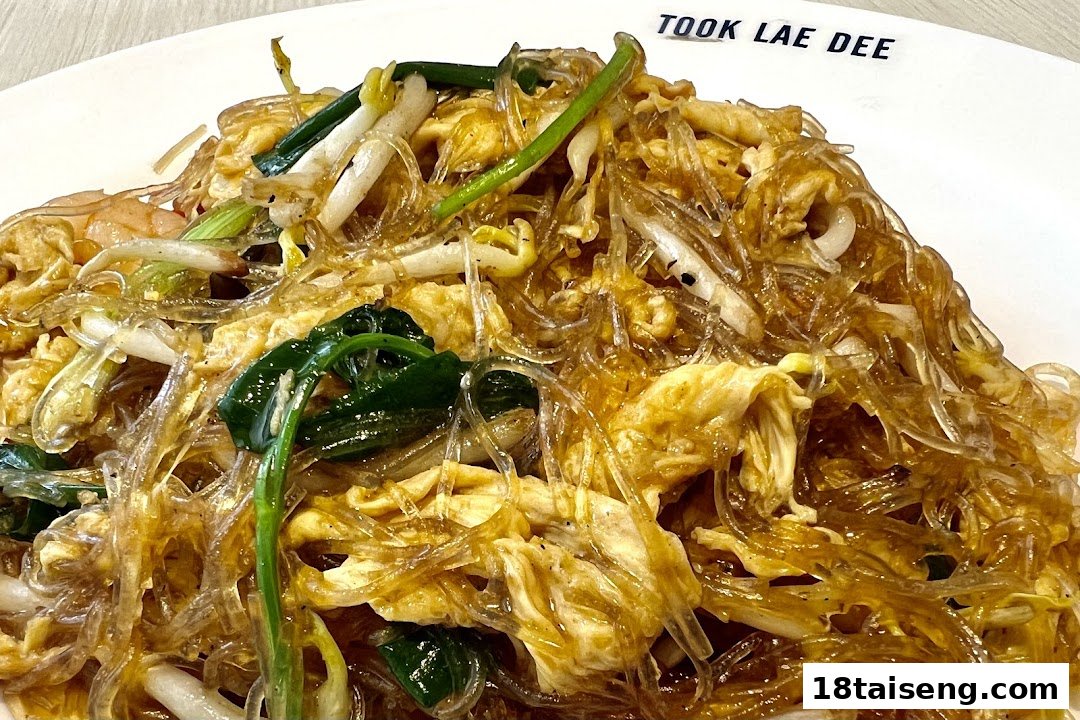 A close-up of stir-fried glass noodles with egg, bean sprouts, and green onions.