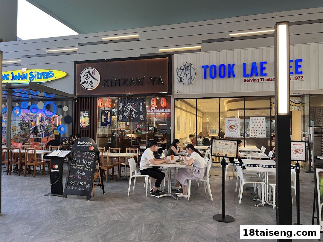 Exterior view of Took Lae Dee restaurant with outdoor seating and neighboring shops.