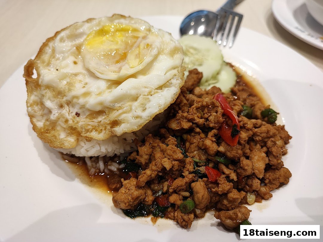 A plate of rice with stir-fried minced meat, basil, chili, and a fried egg.