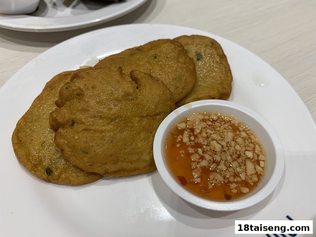 A plate of golden-brown fish cakes served with a sweet and spicy dipping sauce.