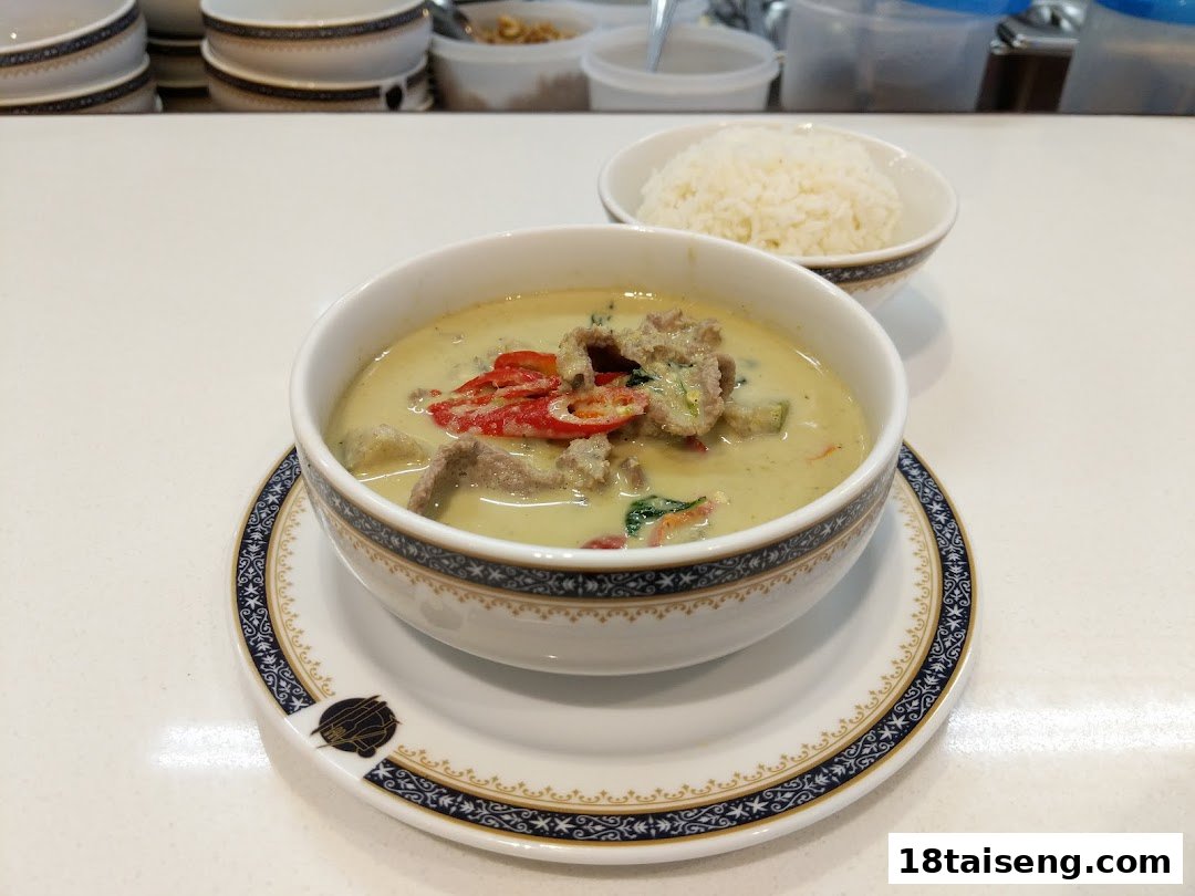 A vibrant bowl of Thai green curry with beef and red chilies, served with a side of steamed rice.