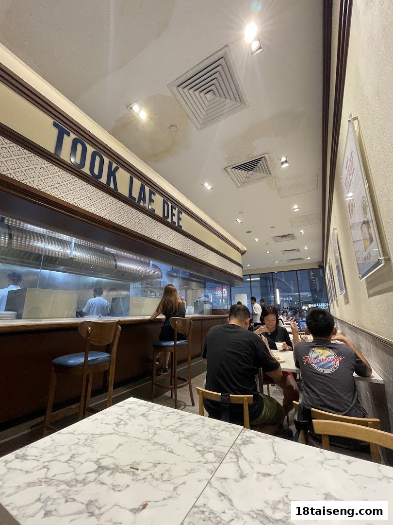 Interior view of Took Lae Dee restaurant with customers dining and an open kitchen visible.