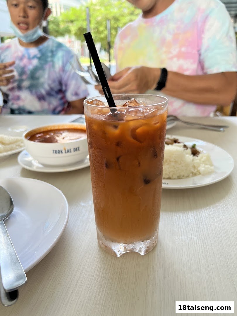 A refreshing iced drink on a table at Took Lae Dee, with diners and food in the background.
