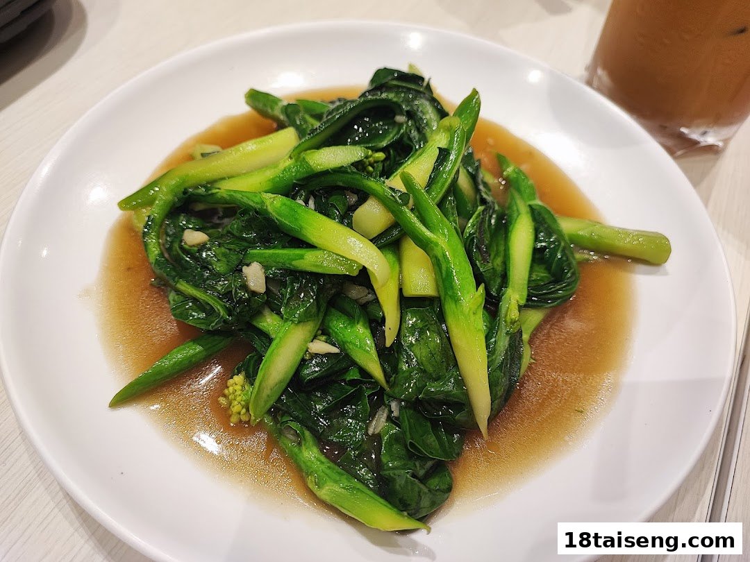 A plate of stir-fried green vegetables, likely Chinese broccoli, in a savory sauce.