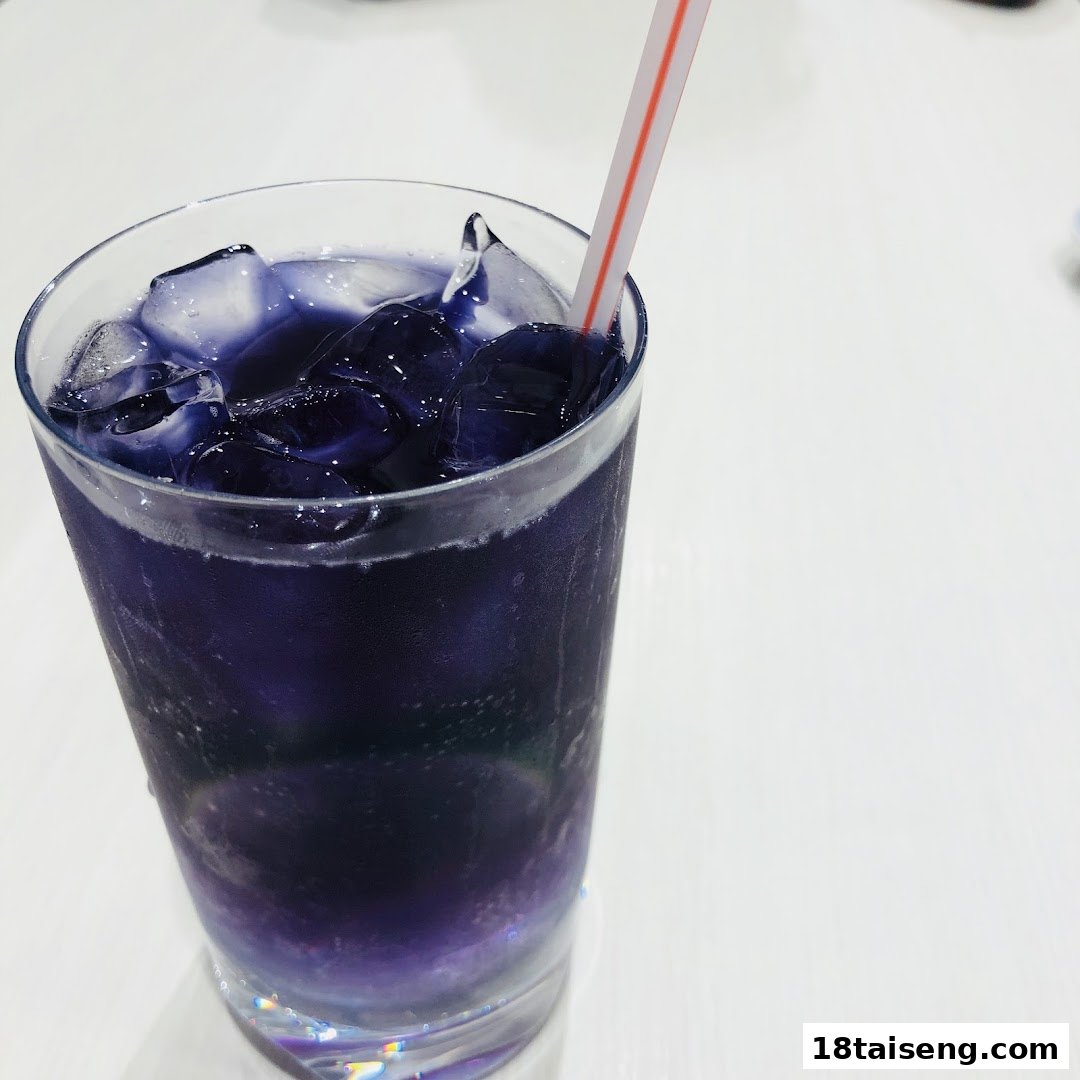 A vibrant purple iced drink with a straw, served on a white table.