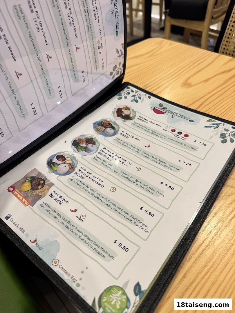 A close-up view of Veggie House's open menu displaying various vegetarian dishes on a wooden table.