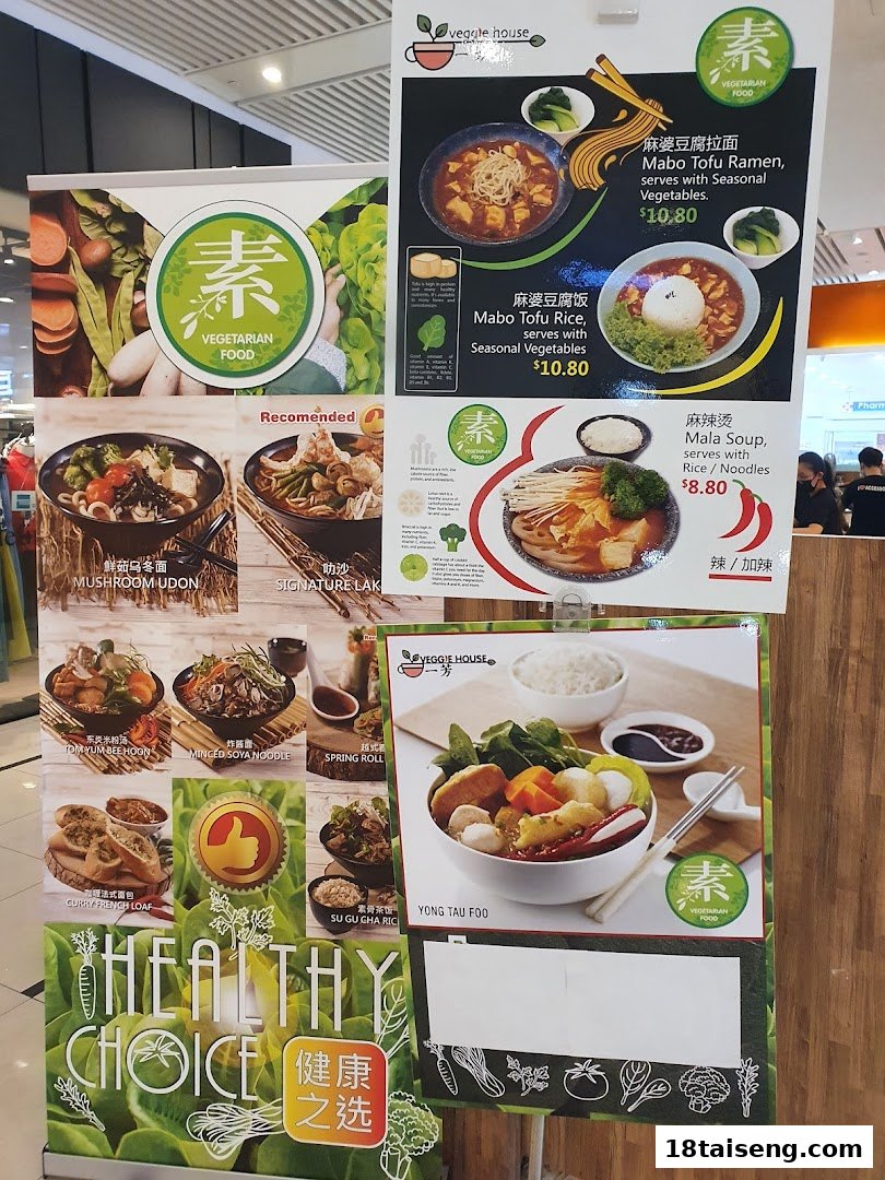 Promotional display boards showcasing a variety of vegetarian dishes with prices and a 'healthy choice' theme.