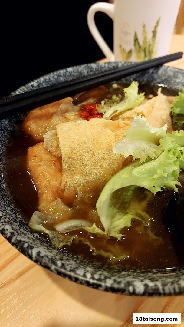 A close-up of a delicious vegetarian dish with tofu skin, lettuce, and broth in a bowl.