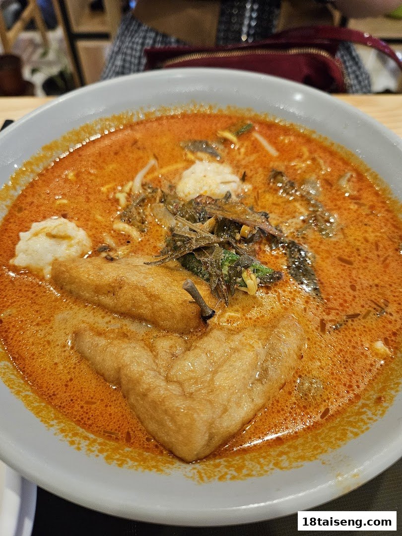 A vibrant bowl of vegetarian curry noodles with tofu puffs and vegetables.