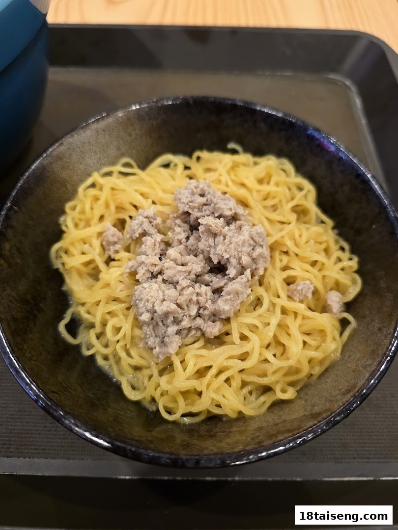 A close-up of a bowl of yellow noodles topped with savory minced vegetarian 'meat'.