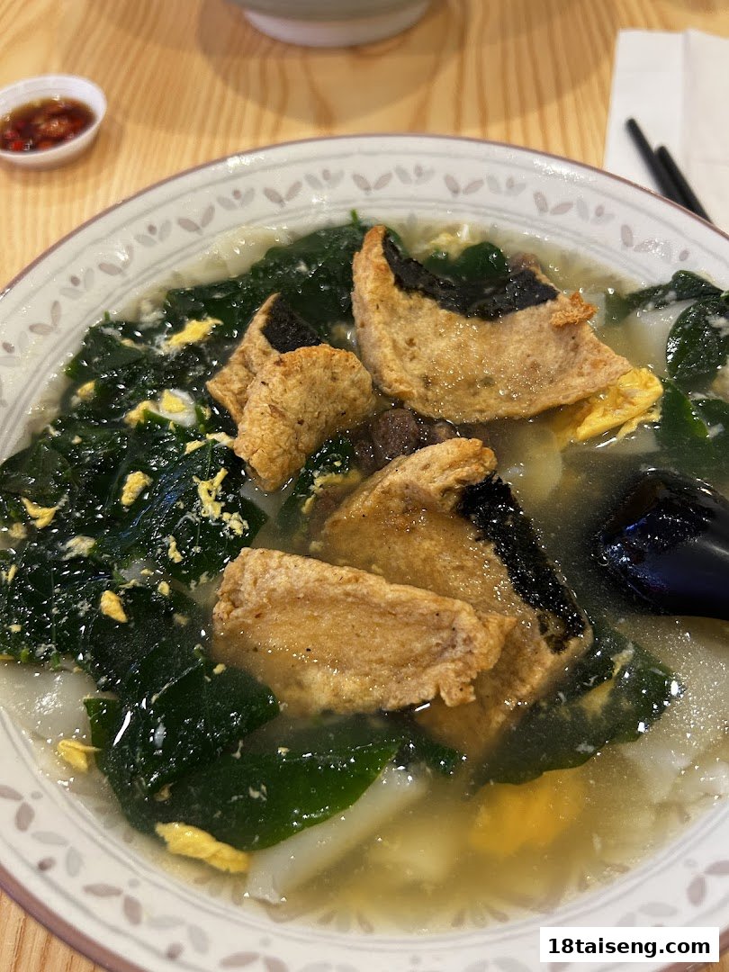 A close-up of a hearty vegetarian soup with tofu, seaweed, and egg in a bowl.