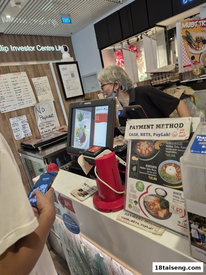 A customer at the cashier counter of Veggie House, showing payment methods and menu items.
