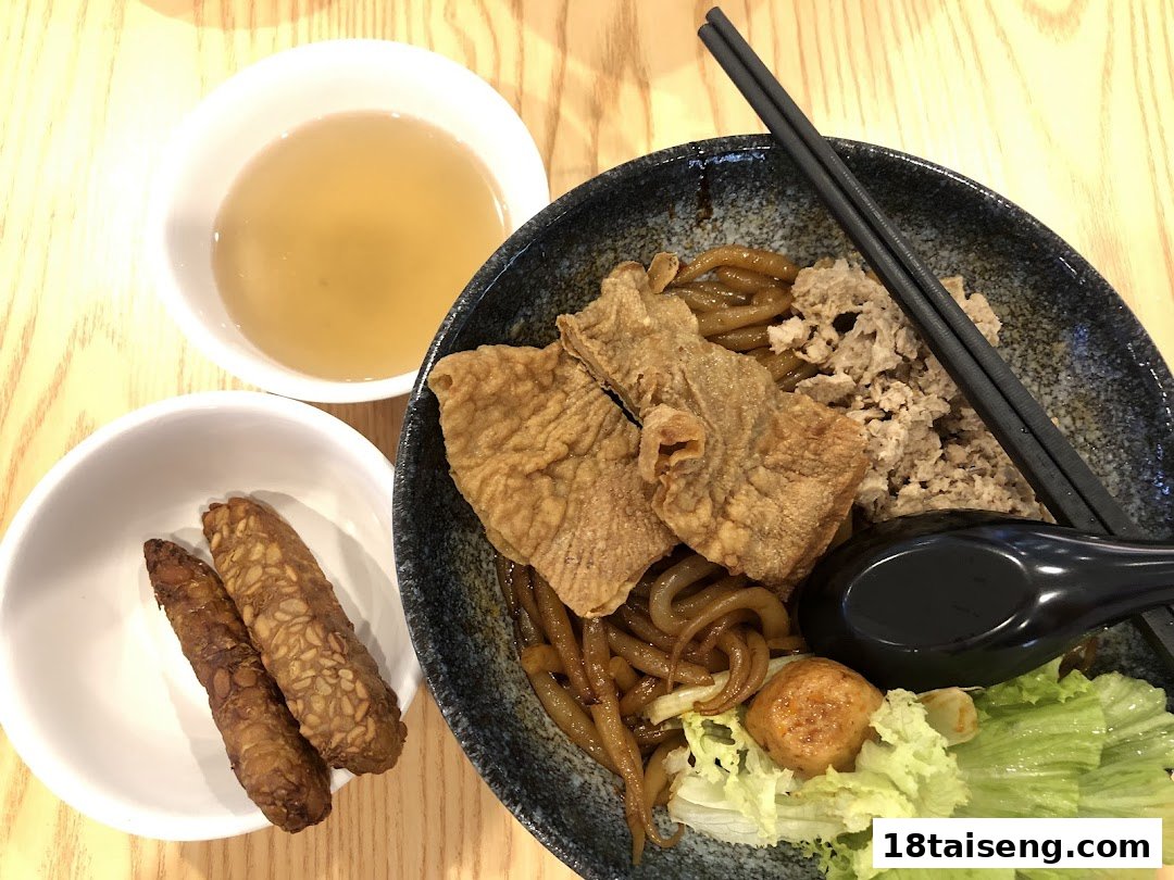 A close-up of a delicious vegetarian noodle dish with crispy sides and a clear soup.