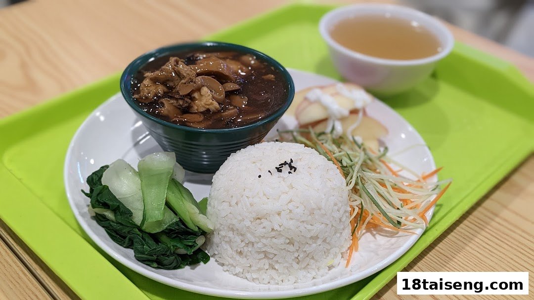 A wholesome vegetarian meal featuring rice, stew, steamed greens, and a side of soup on a green tray.