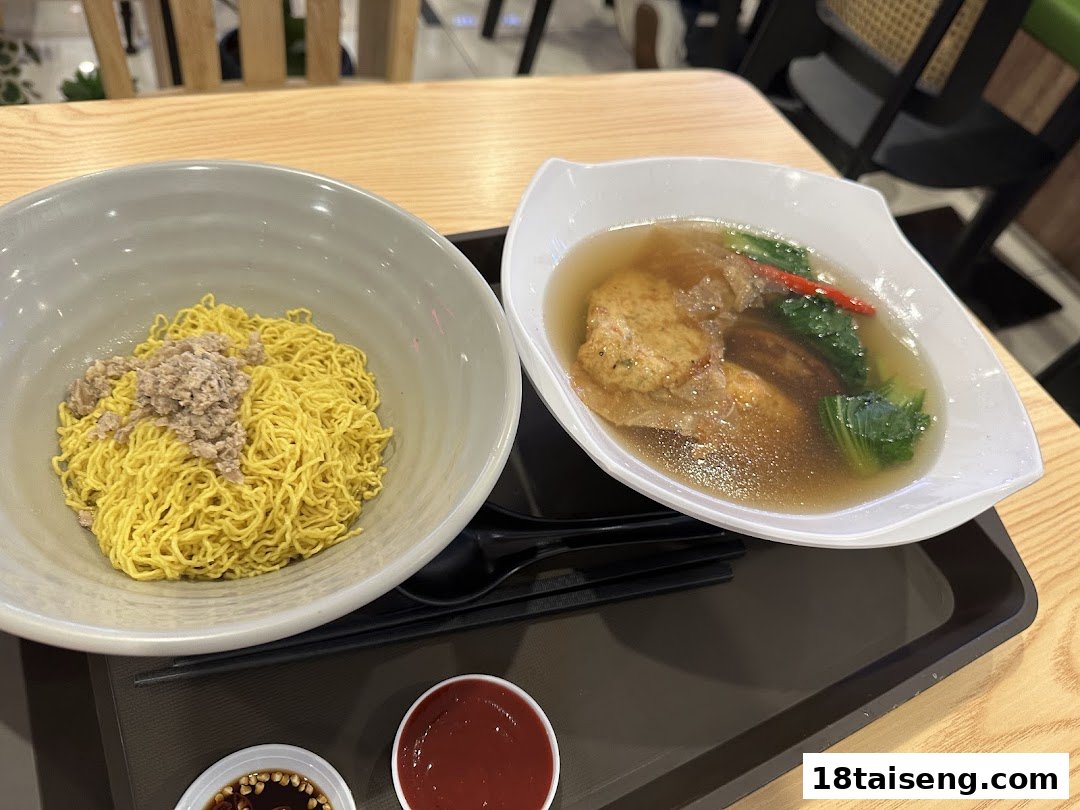 A vegetarian meal featuring dry noodles and a clear soup with vegetables and mock meat.
