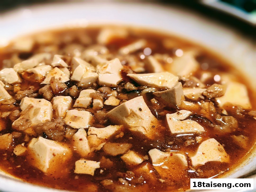 A close-up of a rich, savory tofu dish with a spicy sauce, likely Mapo Tofu.
