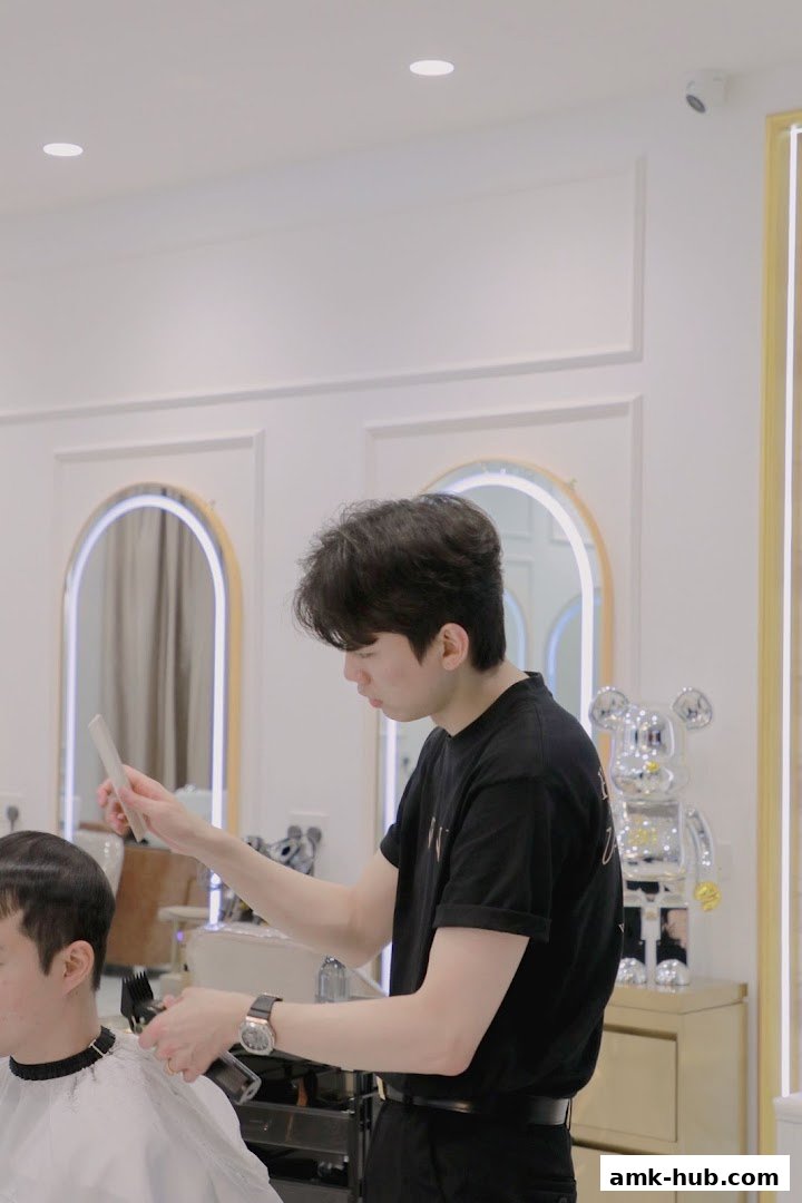 A hairstylist cuts a client's hair with clippers and a comb in a modern salon.