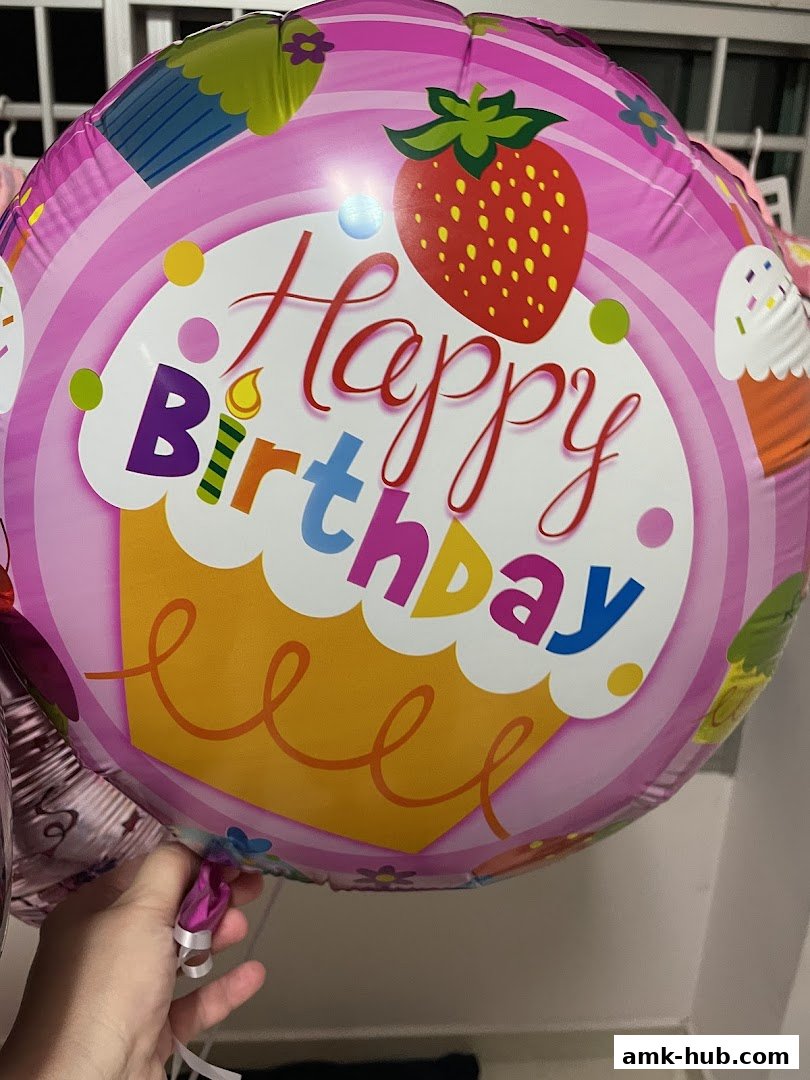 A close-up of a pink birthday balloon with cupcakes and strawberries.