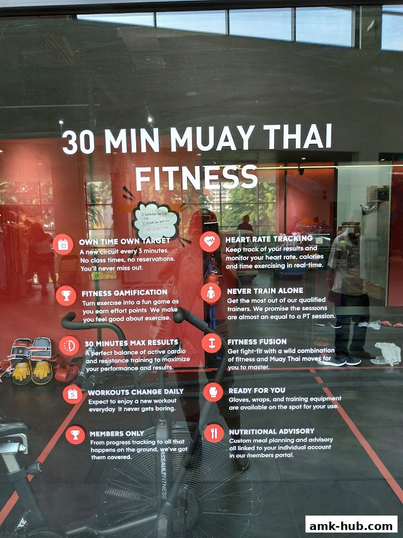 A gym interior showcasing a stationary bike with various fitness program benefits listed on the glass.