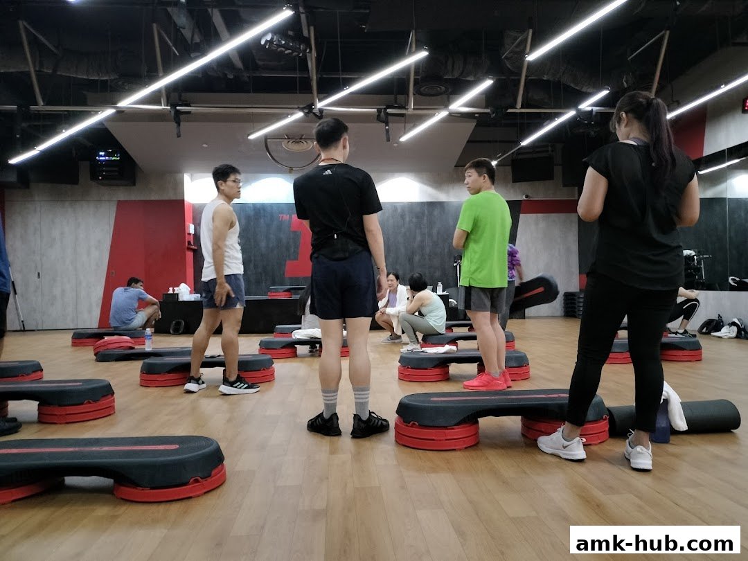 People gathered in a fitness studio with aerobic steps arranged for a class.