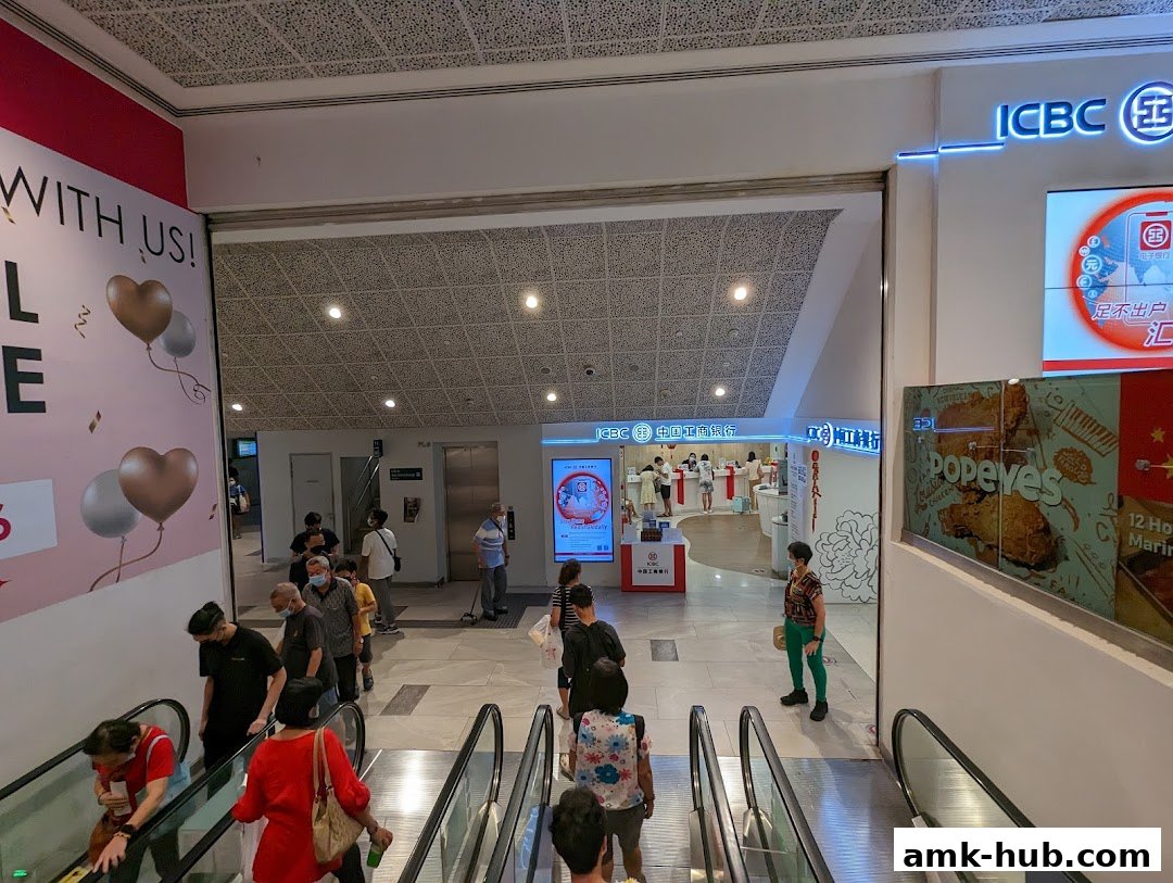 People on escalators near an ICBC bank branch and a Popeyes restaurant.